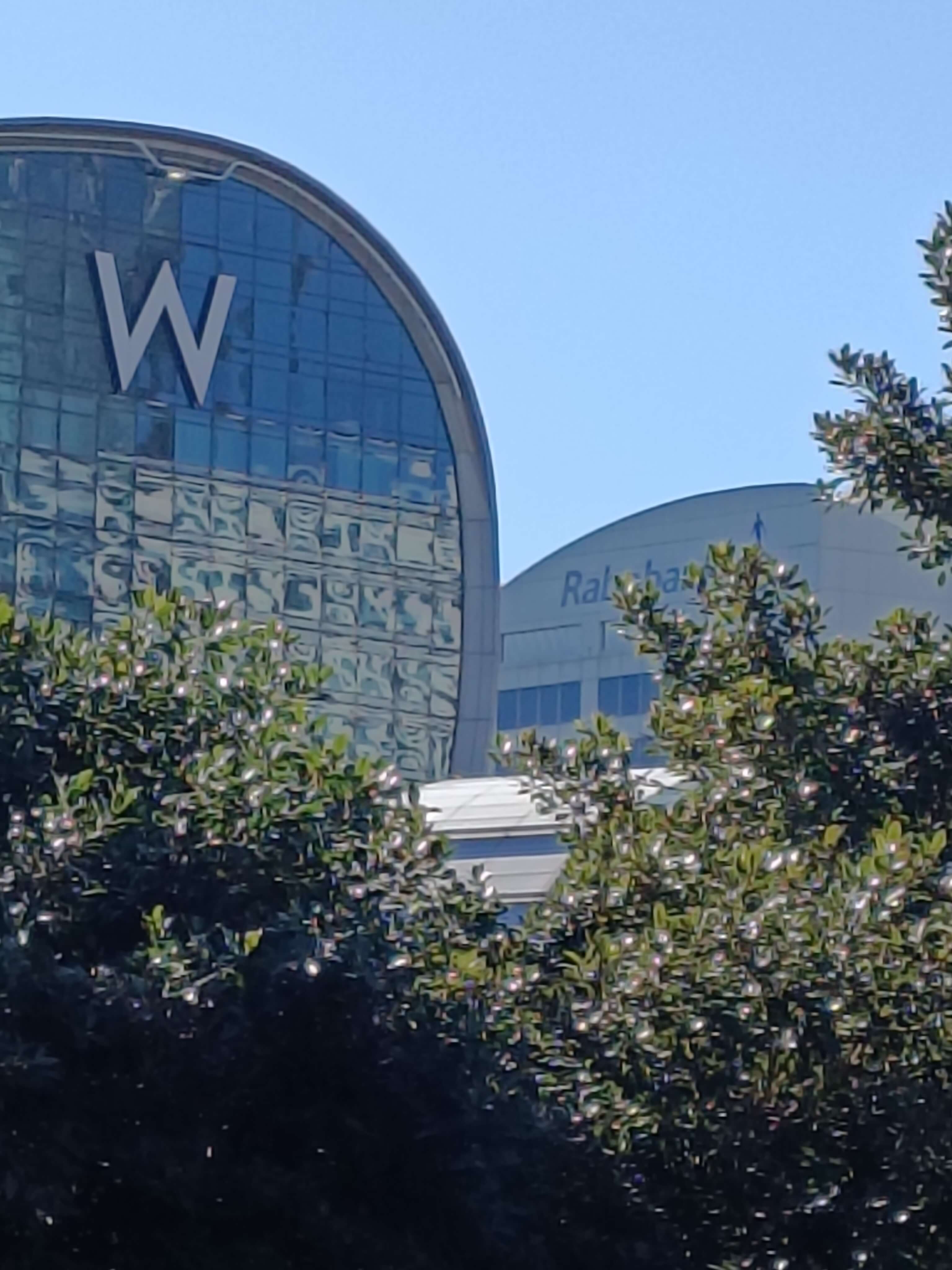 On the left is a building with a 'W' sign on it & on the right is a building with a partially blocked logo called 'Rabobank' on it.