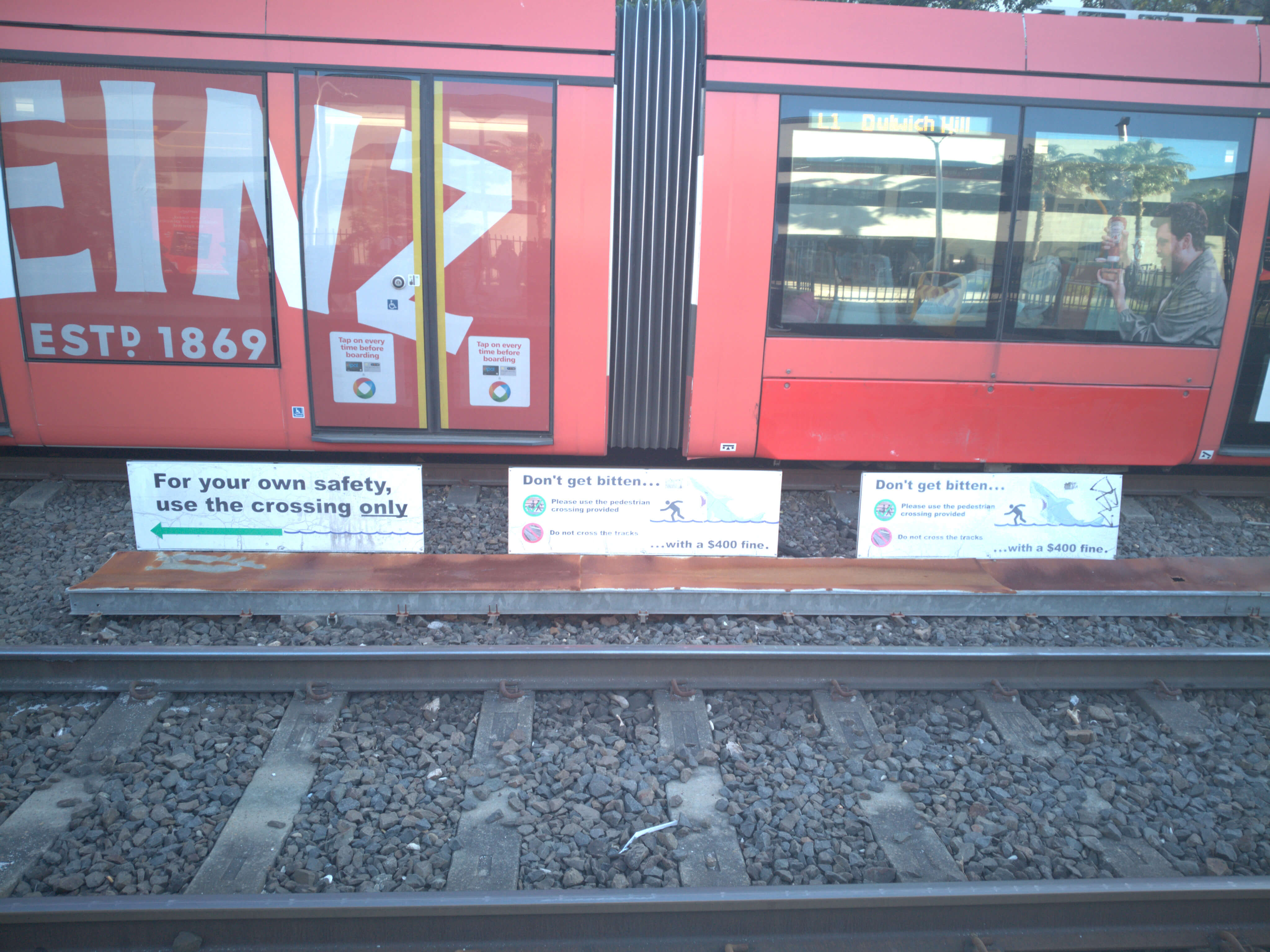 Warning signs about not stepping on the tram tracks or else you will DIE!!!.